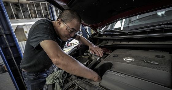 ボンネットを開けて社用車の点検をする整備士